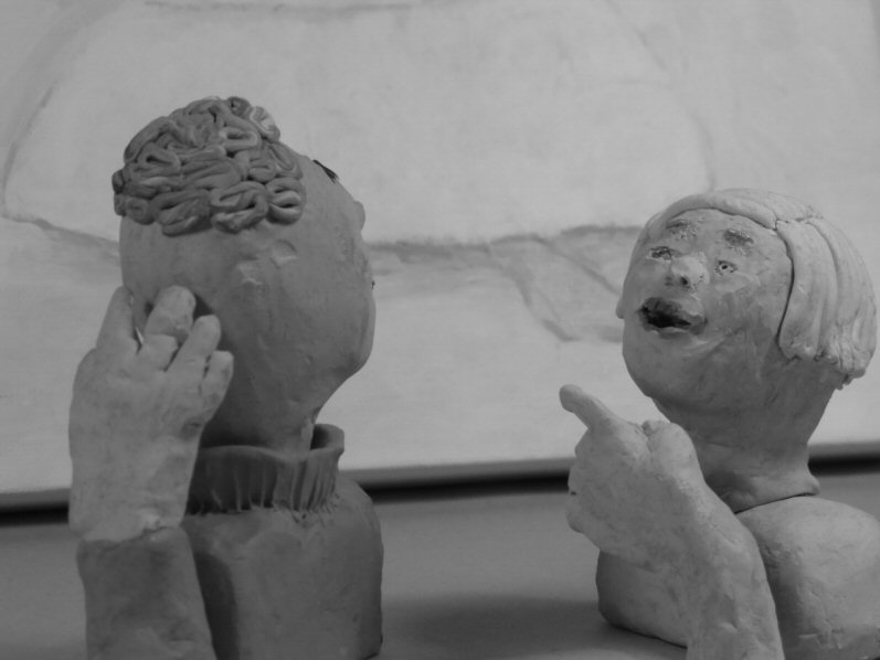 two plasticine heads, one points