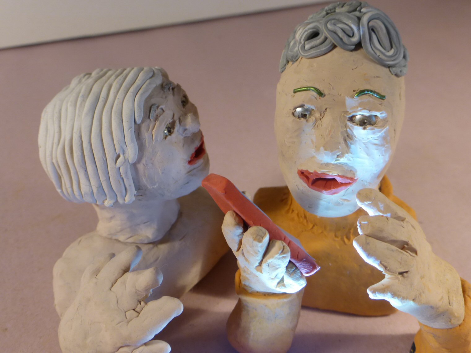 closeup of 2 plasticine heads and smartphone